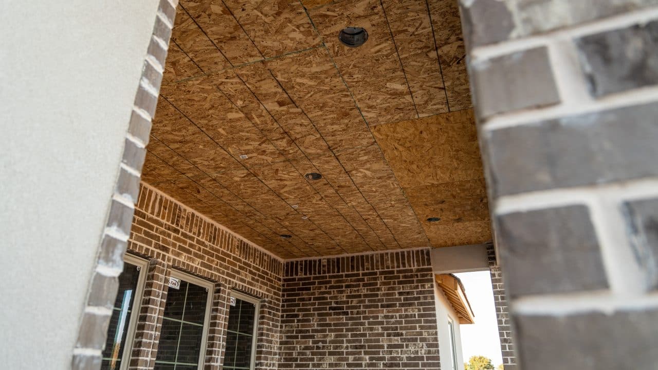 Bare wood sheathing on a covered patio ceiling before soffit work