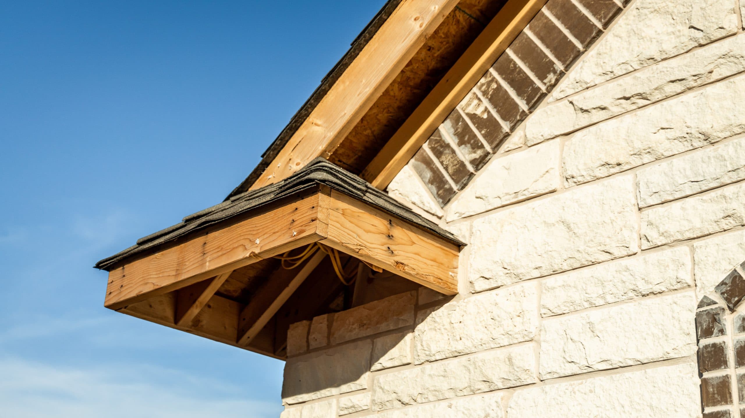 Exposed wood at a gable-end eave before the roof-edge finish was installed