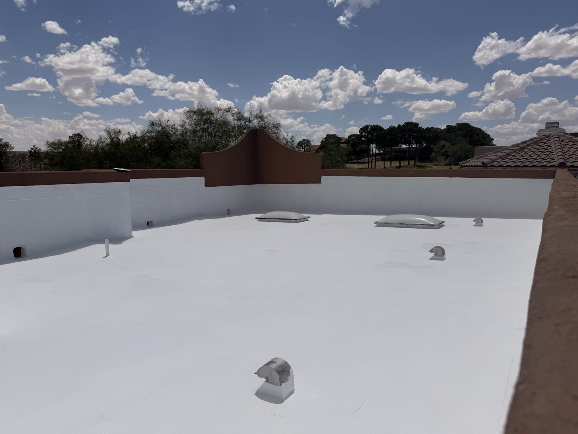 Coated low-slope roof with finished parapet walls