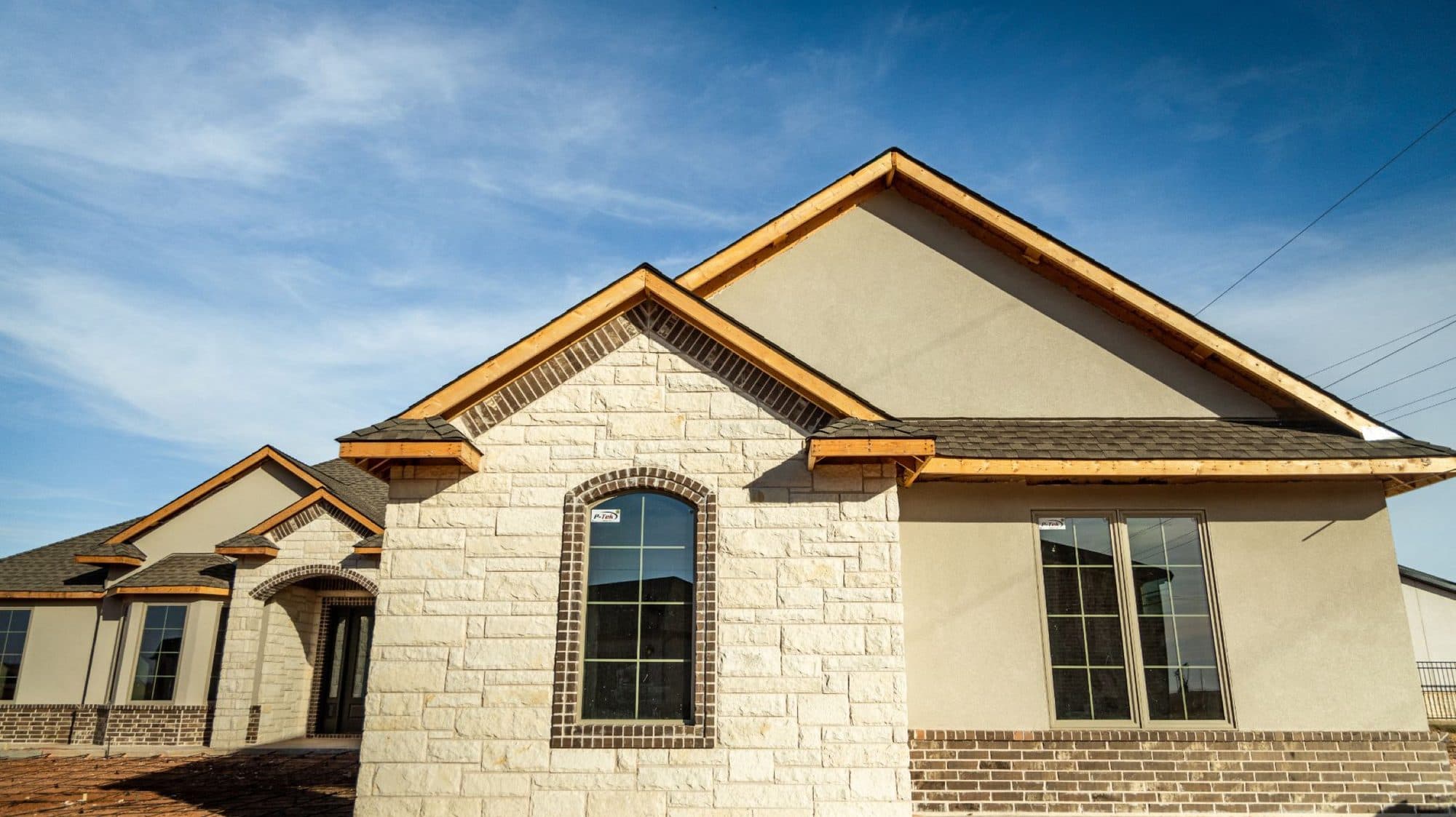 Wide view of a stone and stucco home with finished gables