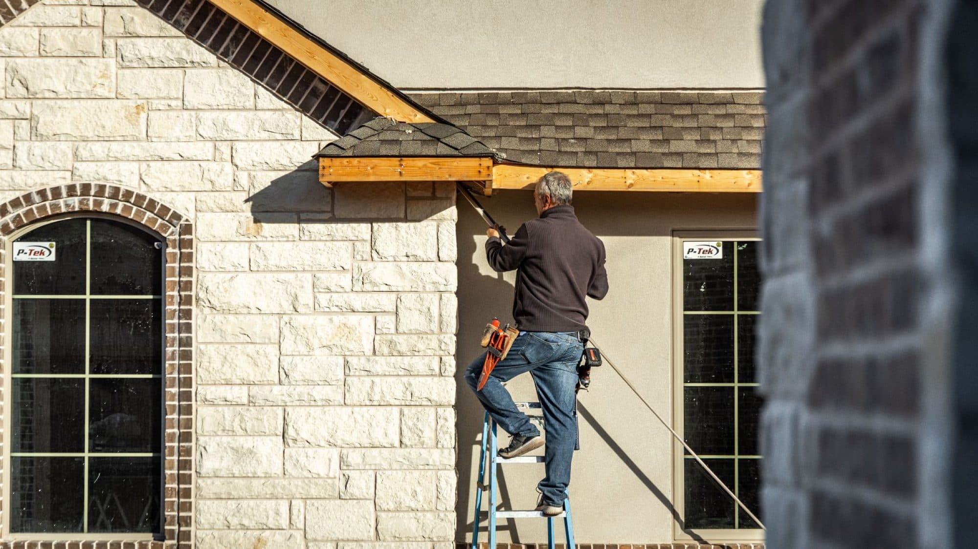 Installer working from a ladder at the eave of a home