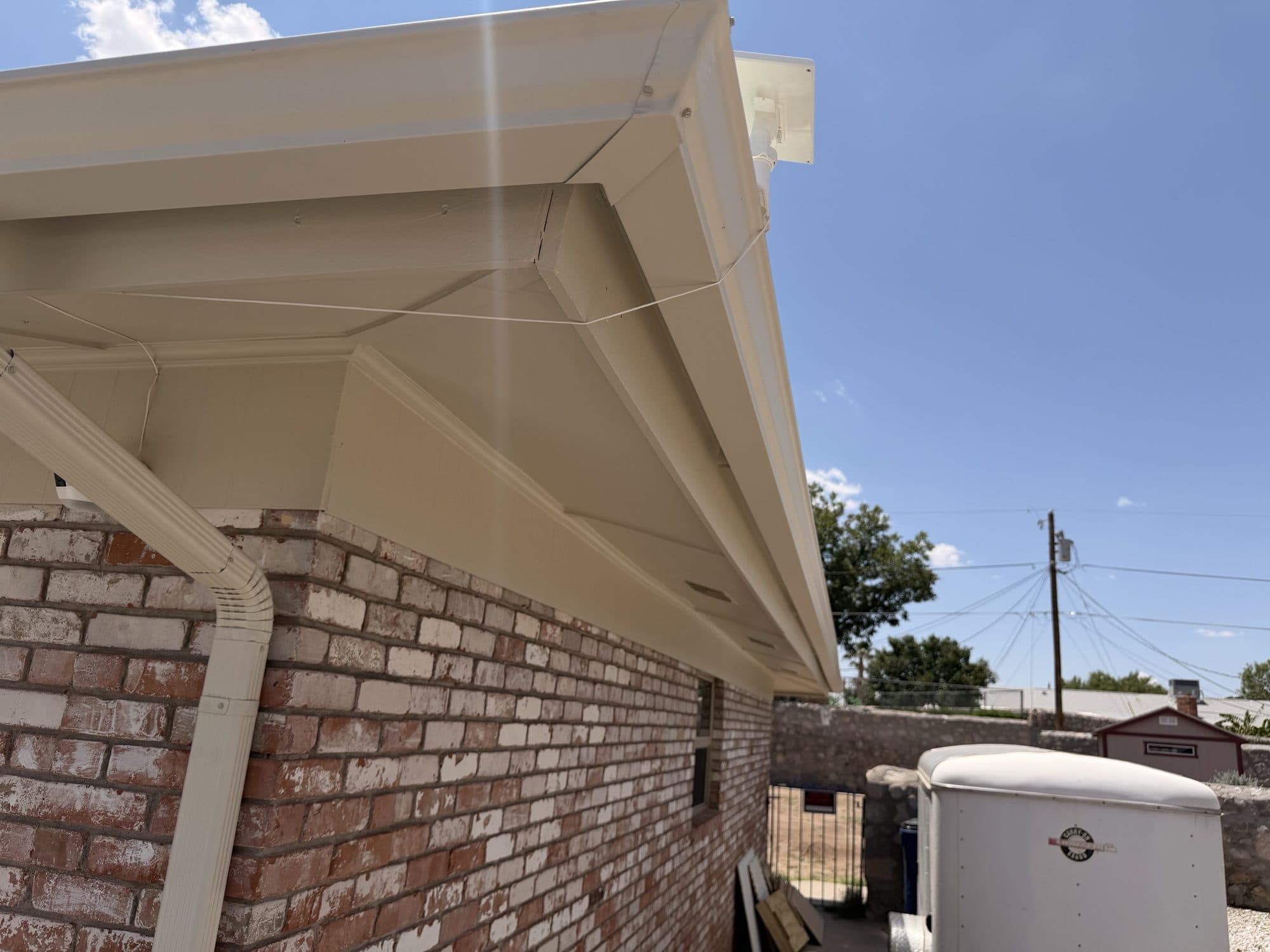 Gutter installed along a white-trimmed gable roofline
